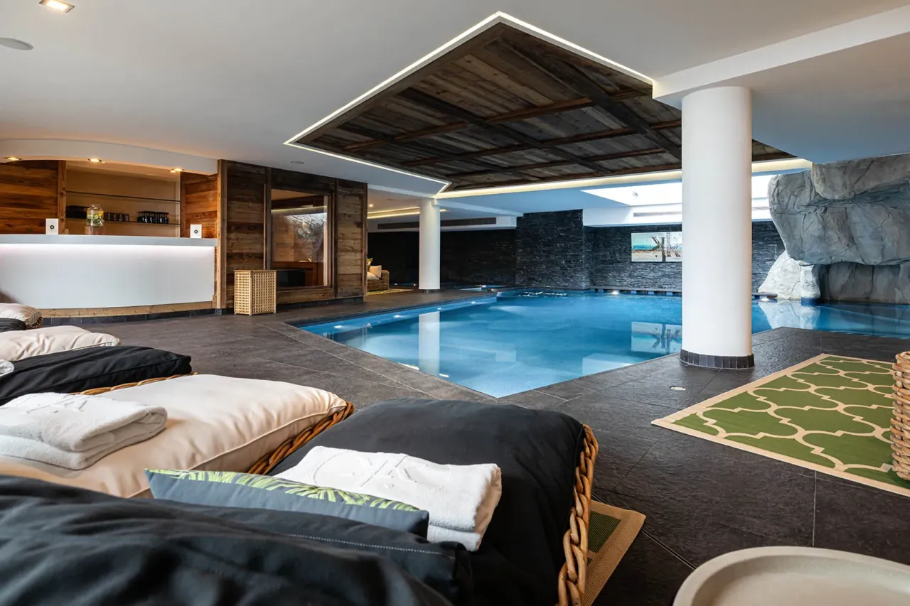 Espace bien-être comprenant une piscine intérieure chauffée, des transats confortables et une décoration minérale avec parois en pierre - Spa Nuxe - Le Kaïla